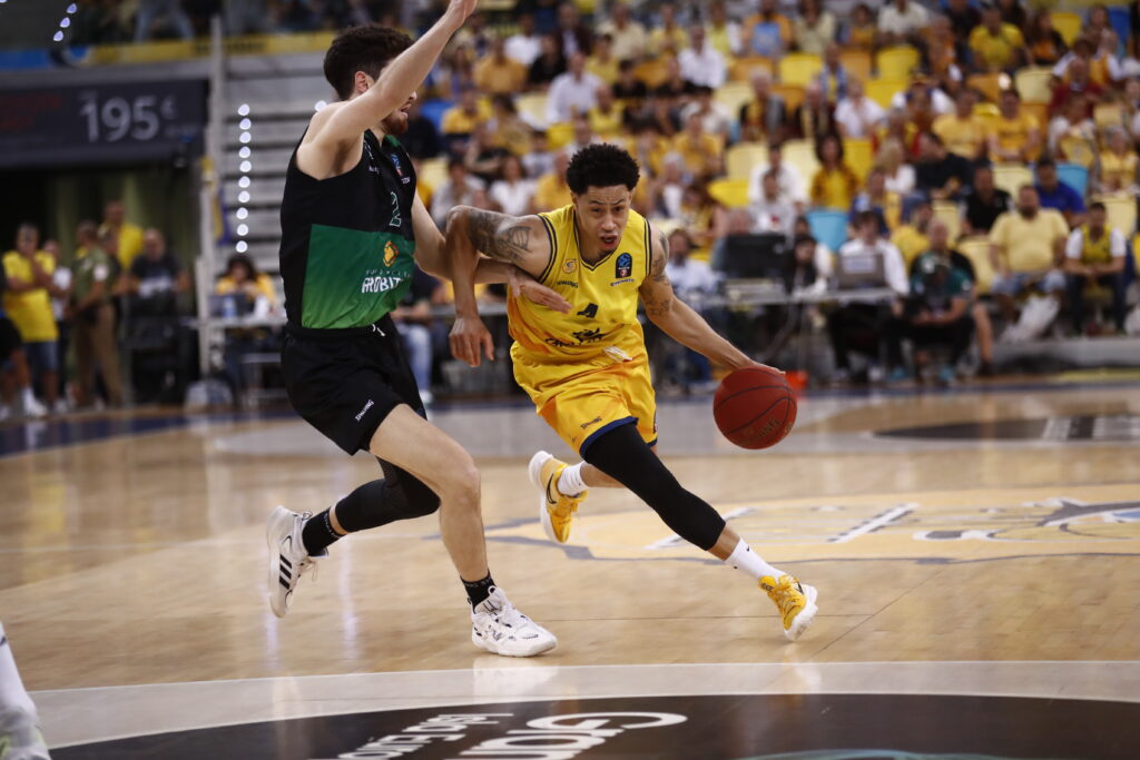 Jugador del Gran Canaria driblando mientras es defendido por un oponente.