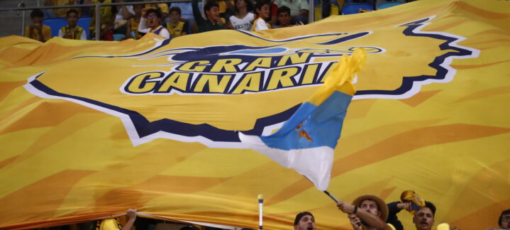 Aficionados del Club Baloncesto Gran Canaria sosteniendo una gran bandera amarilla.