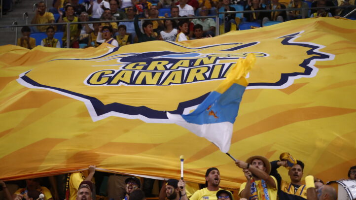 Aficionados del Club Baloncesto Gran Canaria sosteniendo una gran bandera amarilla.