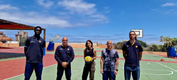 Cuatro personas posan en una cancha de baloncesto bajo un cielo despejado.