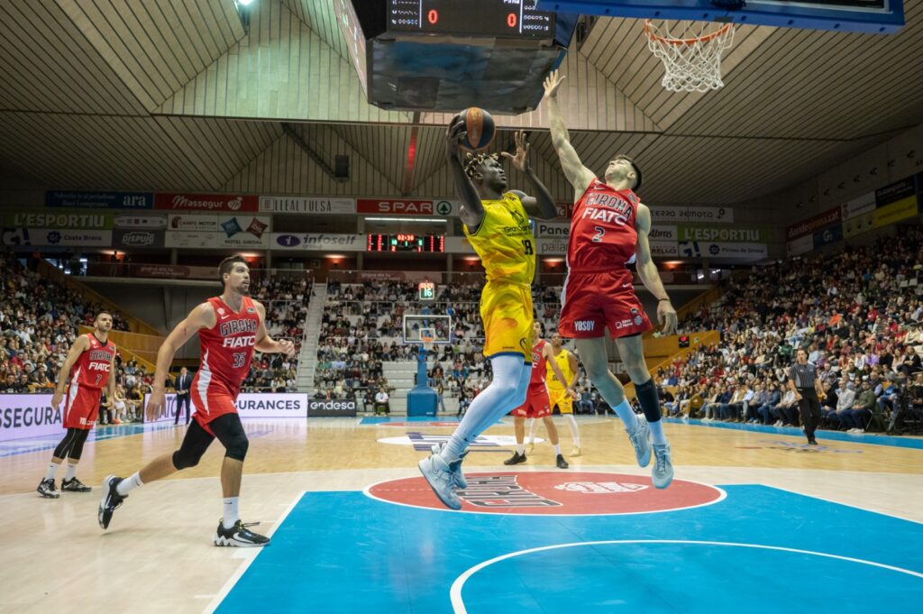  prueba de fuego en el feudo amarillo",Jugadores en acción durante un emocionante partido de baloncesto en un pabellón lleno.