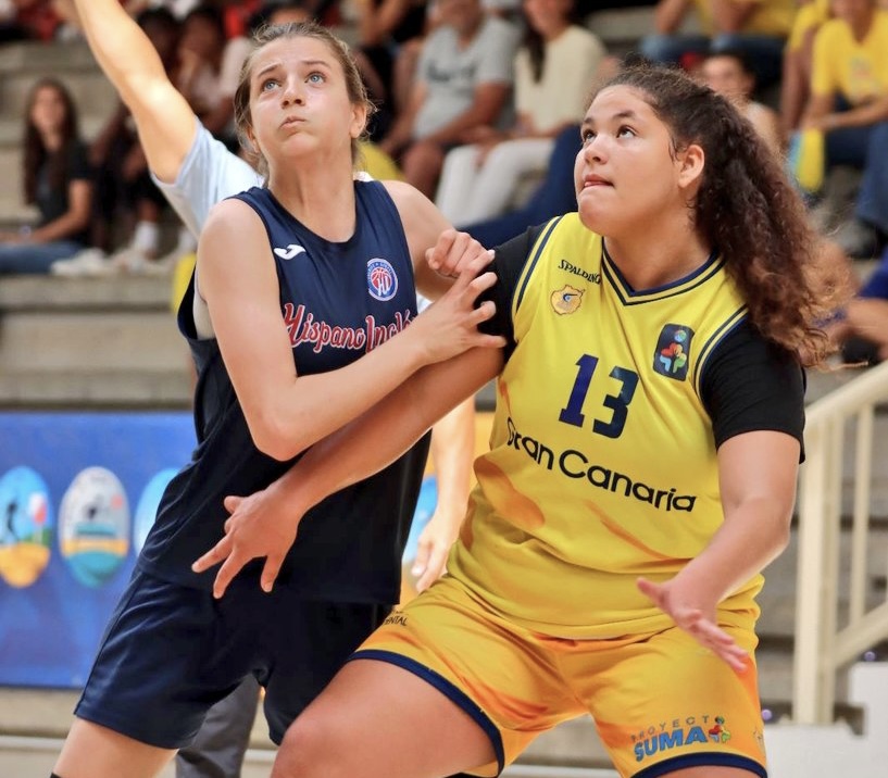 Dos jugadoras de baloncesto compiten por el rebote en un evento deportivo.