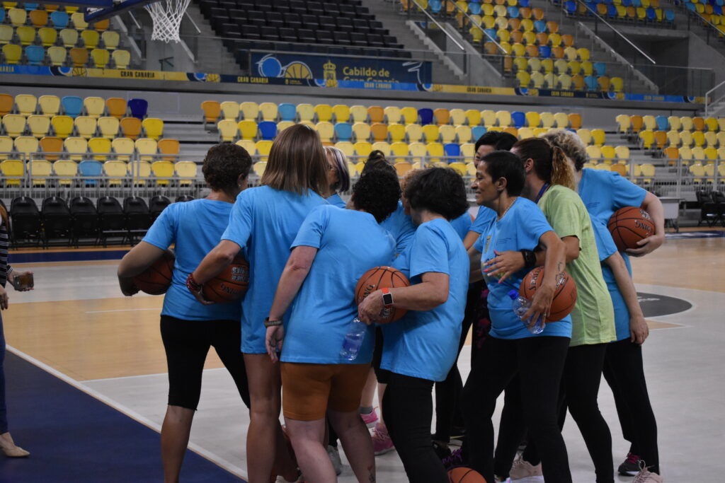 Jugadoras en el Gran Canaria Arena se agrupan, preparándose para un partido de baloncesto.