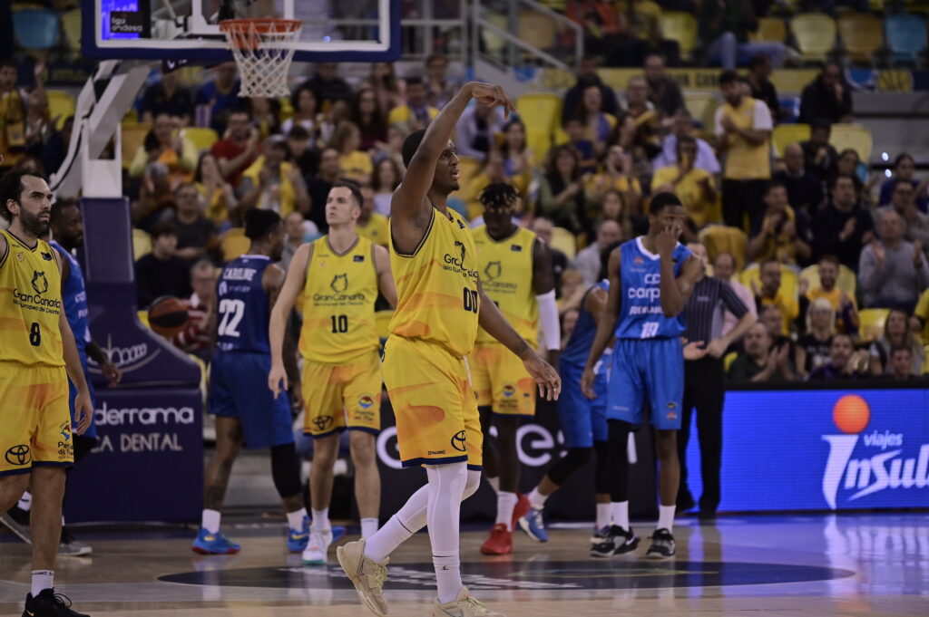 Jugadores del Gran Canaria en acción durante un partido, con el público al fondo.