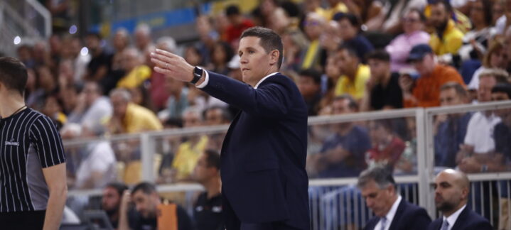 Entrenador dirigiendo al equipo durante un partido ante un público numeroso.