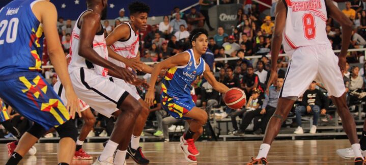 Jugadores en acción durante un partido de baloncesto, se observa a Edson Tovar con el balón.