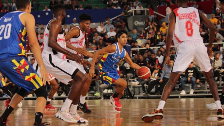 Jugadores en acción durante un partido de baloncesto, se observa a Edson Tovar con el balón.