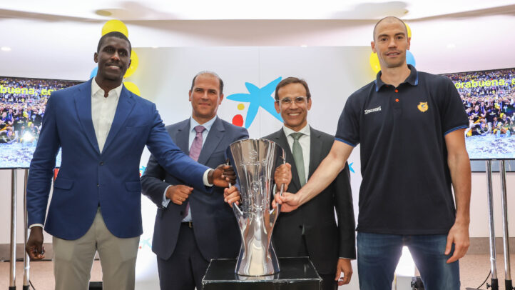 Cuatro personas sostienen un trofeo en un evento del CB Gran Canaria con decoraciones festivas.