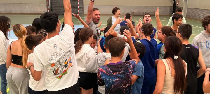 Grupo de unos 50 jóvenes celebrando en un entrenamiento en un gimnasio.