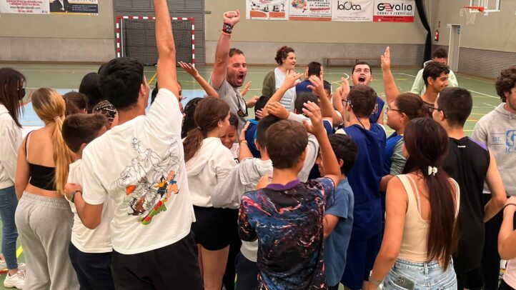 Grupo de unos 50 jóvenes celebrando en un entrenamiento en un gimnasio.