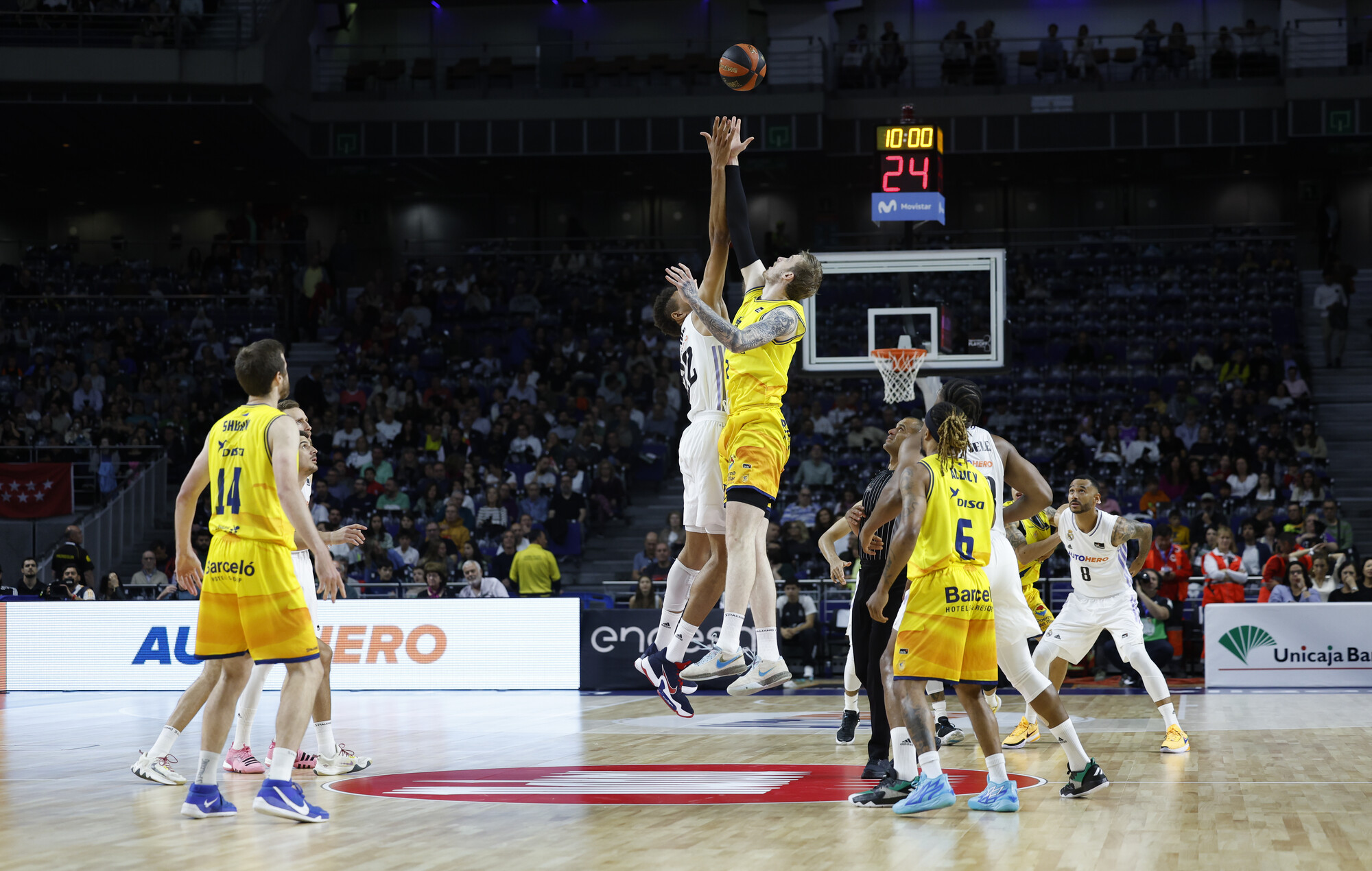 Jugadores saltando para el salto inicial en un partido de baloncesto en el Gran Canaria Arena.