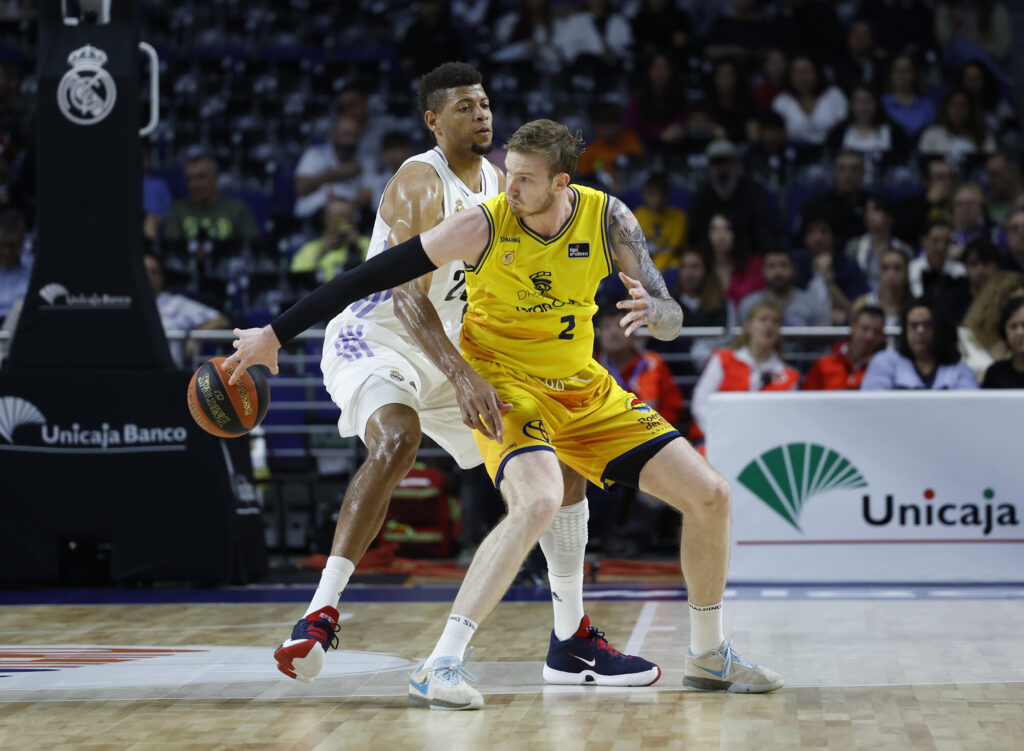 Dos jugadores de baloncesto compiten en la cancha durante un partido emocionante.