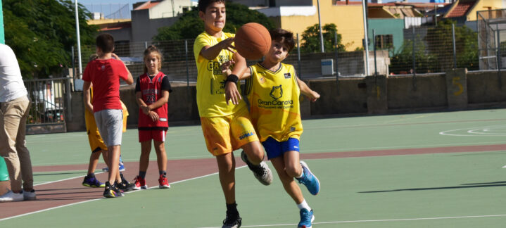 Niños jugando baloncesto en una cancha, lanzando y recibiendo un balón.