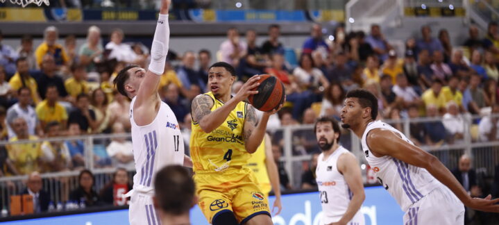 AJ Slaughter lanza a canasta mientras es defendido por jugadores rivales en un partido.