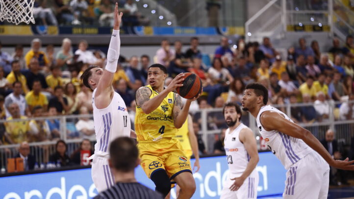 AJ Slaughter lanza a canasta mientras es defendido por jugadores rivales en un partido.