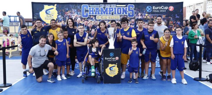 Grupo de jóvenes y adultos con trofeo, celebrando en la cancha del CB Gran Canaria.
