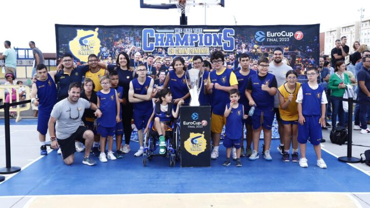Grupo de jóvenes y adultos con trofeo, celebrando en la cancha del CB Gran Canaria.