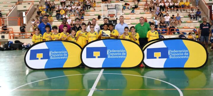Grupo de niños del preminibasket con trofeo, rodeados de entrenadores y carteles del club.
