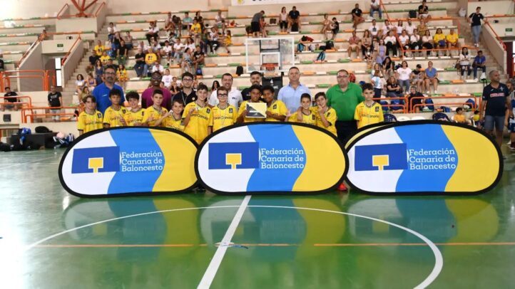 Grupo de niños del preminibasket con trofeo, rodeados de entrenadores y carteles del club.