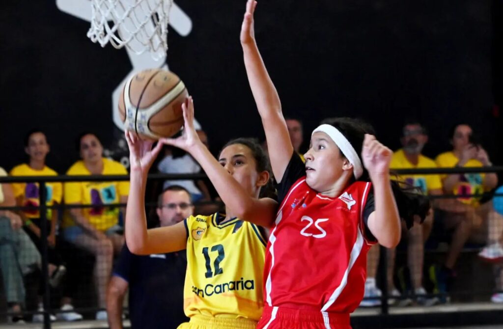 Jugadoras en acción durante un partido de preminibasket femenino en un gimnasio.