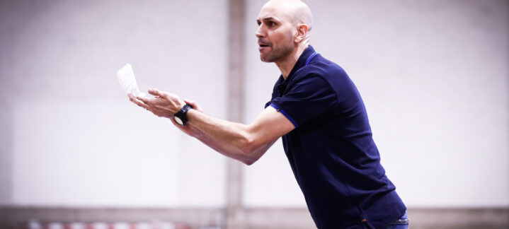 Entrenador gesticulando y dirigiendo el entrenamiento del equipo de baloncesto.