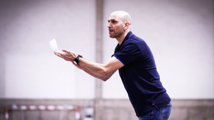 Entrenador gesticulando y dirigiendo el entrenamiento del equipo de baloncesto.