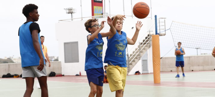 Niños en la cancha de baloncesto durante el campus de verano, practicando el pase.