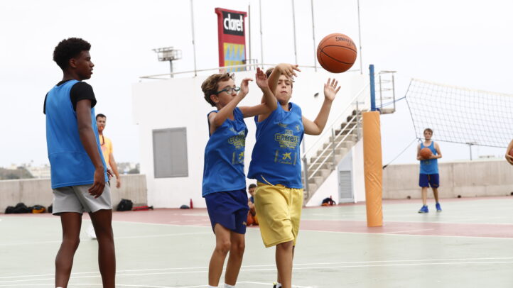Niños en la cancha de baloncesto durante el campus de verano, practicando el pase.