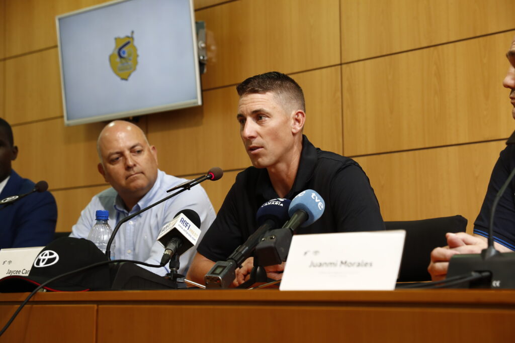 protagonista en Toyota Canarias como estrella invitada del XLII Campus de Verano CaixaBank",Jaycee Carroll habla en una mesa redonda con otros asistentes y micrófonos.