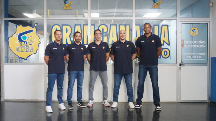 Grupo de cinco personas en uniforme del CB Gran Canaria, frente a una pared con el logo del club.