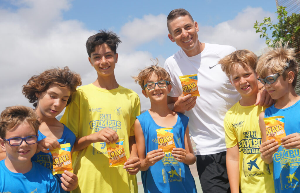  gran protagonista en el XLII Campus de Verano CaixaBank del CB Gran Canaria",Grupo de jóvenes y un entrenador sosteniendo productos Kellogg's en el campus de baloncesto.