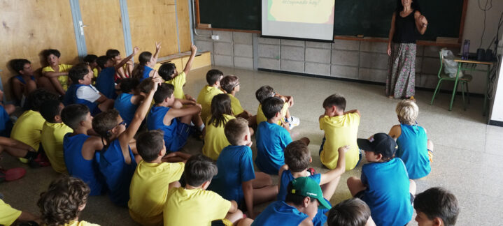 Grupo de niños escuchando a una instructora en el Campus de Verano CaixaBank.