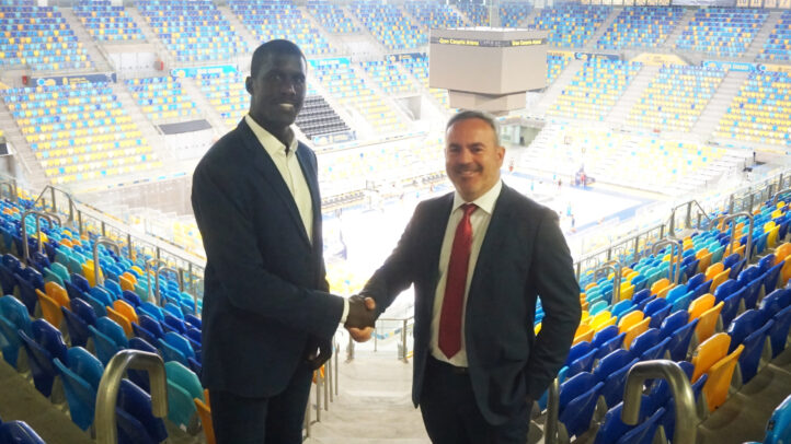 Dos personas se estrechan la mano en un estadio, celebrando un nuevo patrocinio.