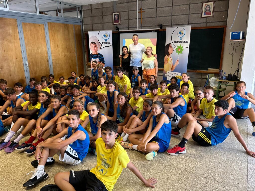 Grupo de jóvenes en el XLII Campus de Verano CaixaBank, con carteles de actividades.