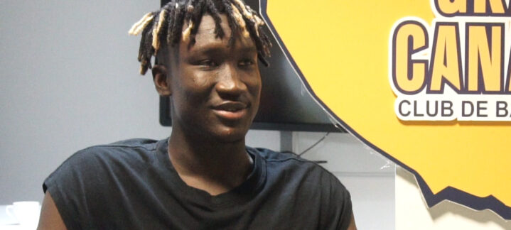 Khalifa Diop sonríe mientras se despide en una entrevista con el logo del club detrás.