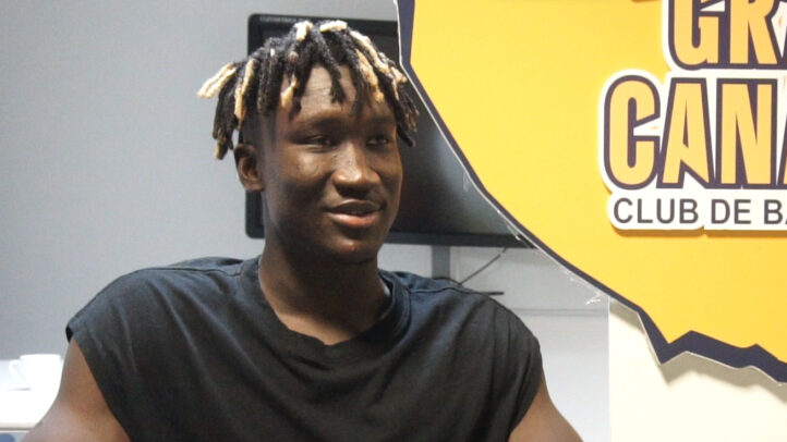 Khalifa Diop sonríe mientras se despide en una entrevista con el logo del club detrás.