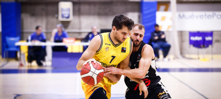 Jugadores de baloncesto compiten por el balón en un partido en la cancha.