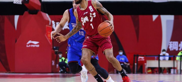 Jugador con balón en acción durante un partido de baloncesto, defendido por otro.