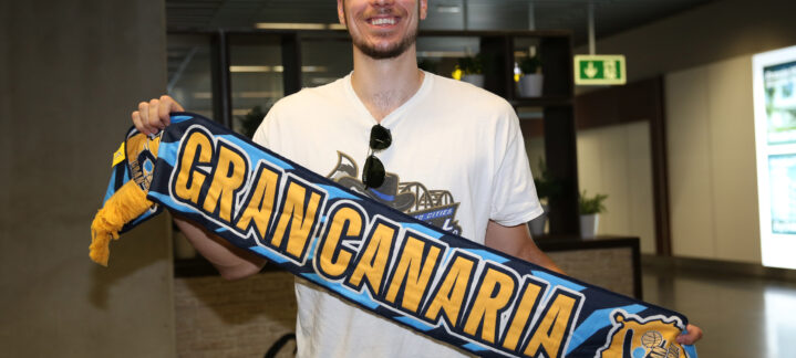 Jugador sonriente sosteniendo una bufanda del Club Baloncesto Gran Canaria.