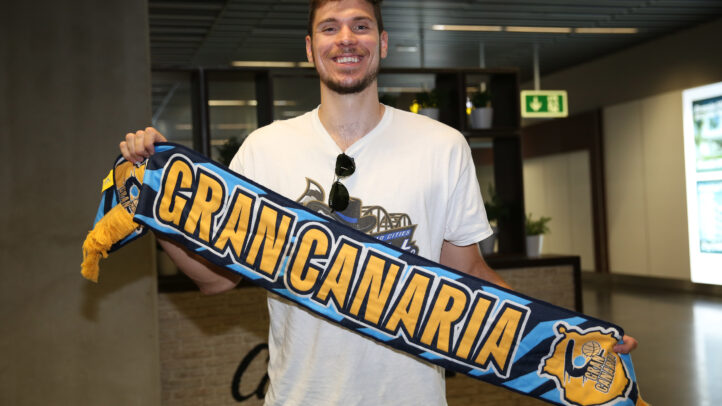 Jugador sonriente sosteniendo una bufanda del Club Baloncesto Gran Canaria.
