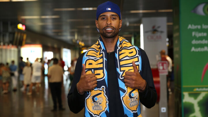 Jugador del Gran Canaria sonriente, con una bufanda del equipo y haciendo gestos positivos.