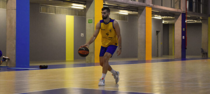 Jugador entrenando en cancha de baloncesto, driblando un balón con buena concentración.