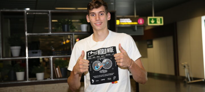 Jugador sonriente mostrando una camiseta con un diseño gráfico, en un entorno interior.