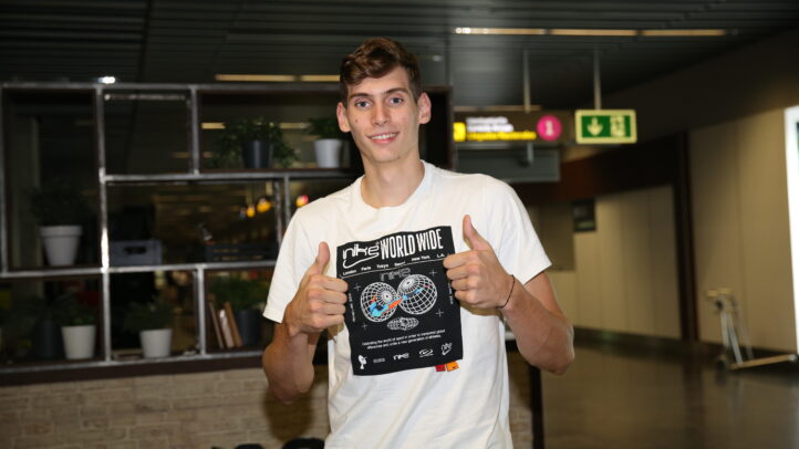 Jugador sonriente mostrando una camiseta con un diseño gráfico, en un entorno interior.