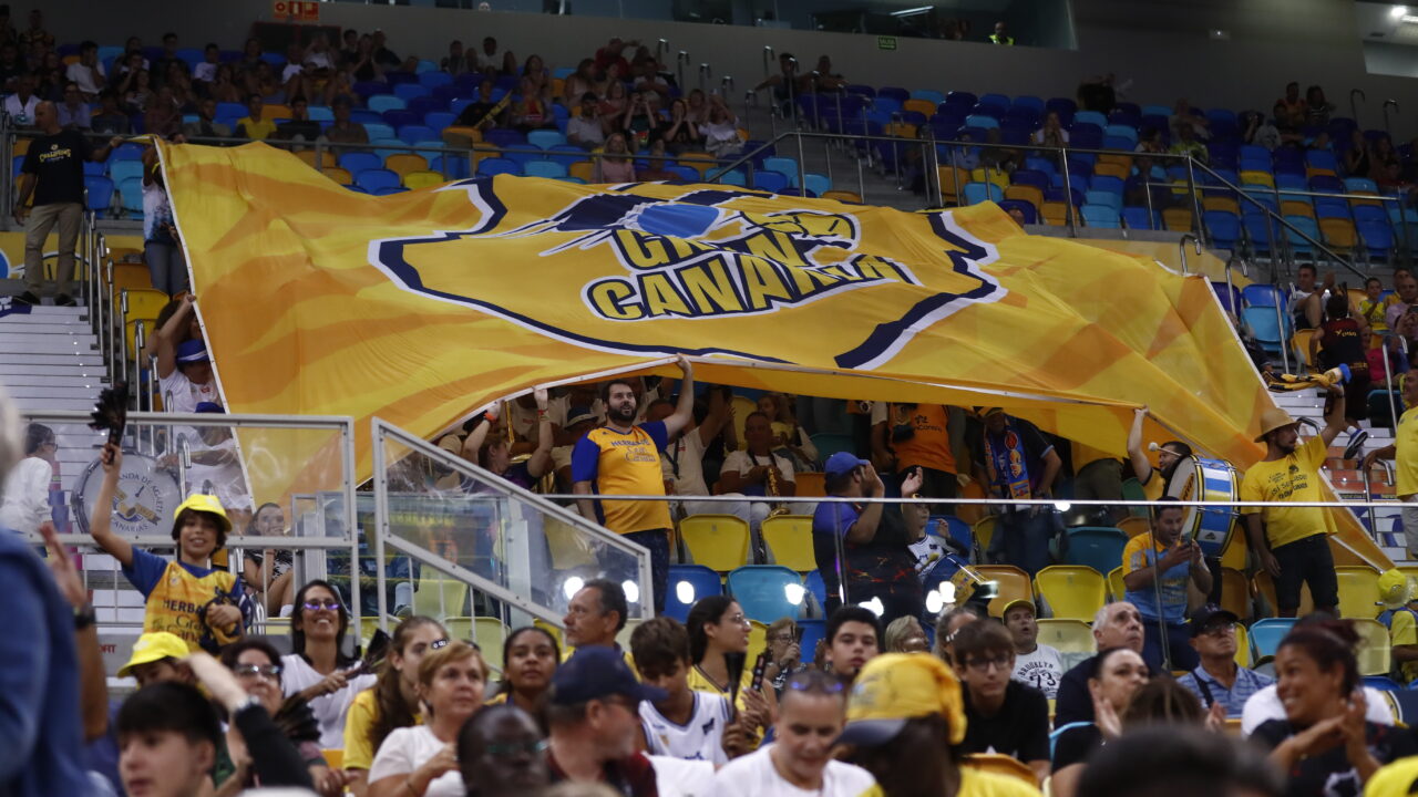 Aficionados del Club Baloncesto Gran Canaria ondeando una gran bandera en un partido.