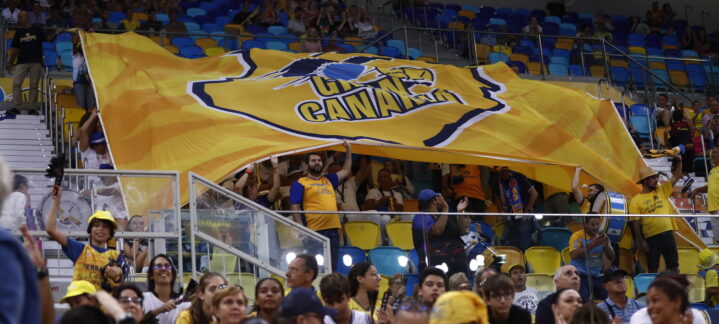 Aficionados del Club Baloncesto Gran Canaria ondeando una gran bandera en un partido.