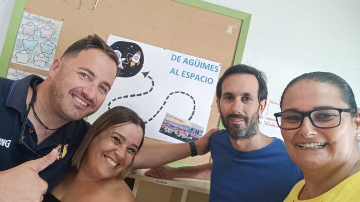 Cuatro personas sonrientes posan junto a un cartel del Proyecto Suma 5.0.