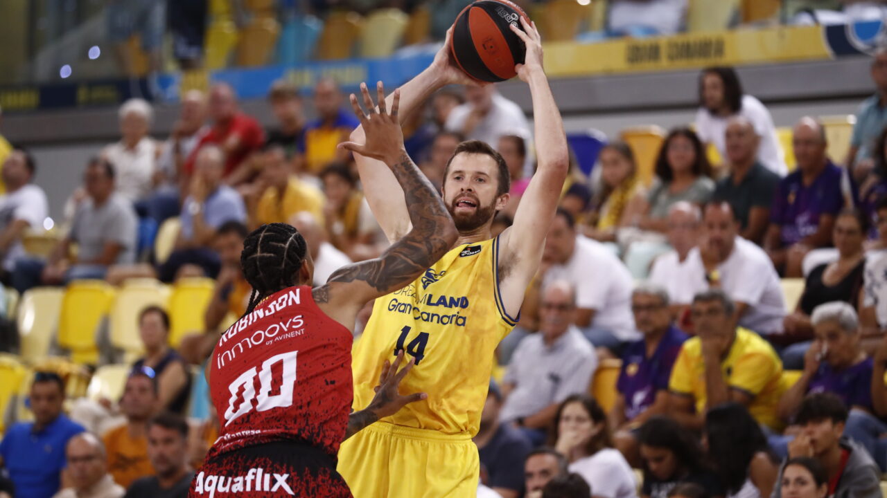 Jugador del Dreamland Gran Canaria lanza el balón mientras es defendido por un oponente.