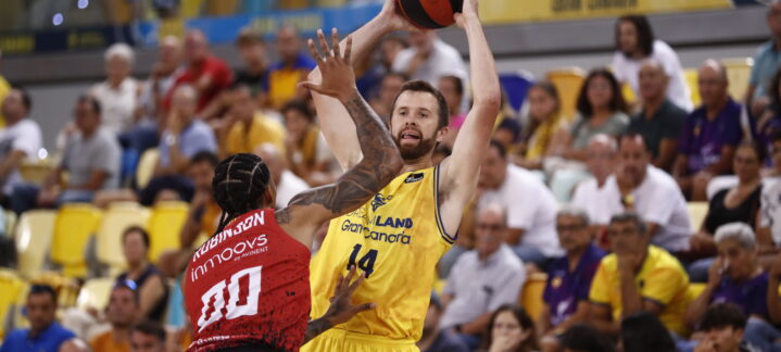 Jugador del Dreamland Gran Canaria lanza el balón mientras es defendido por un oponente.