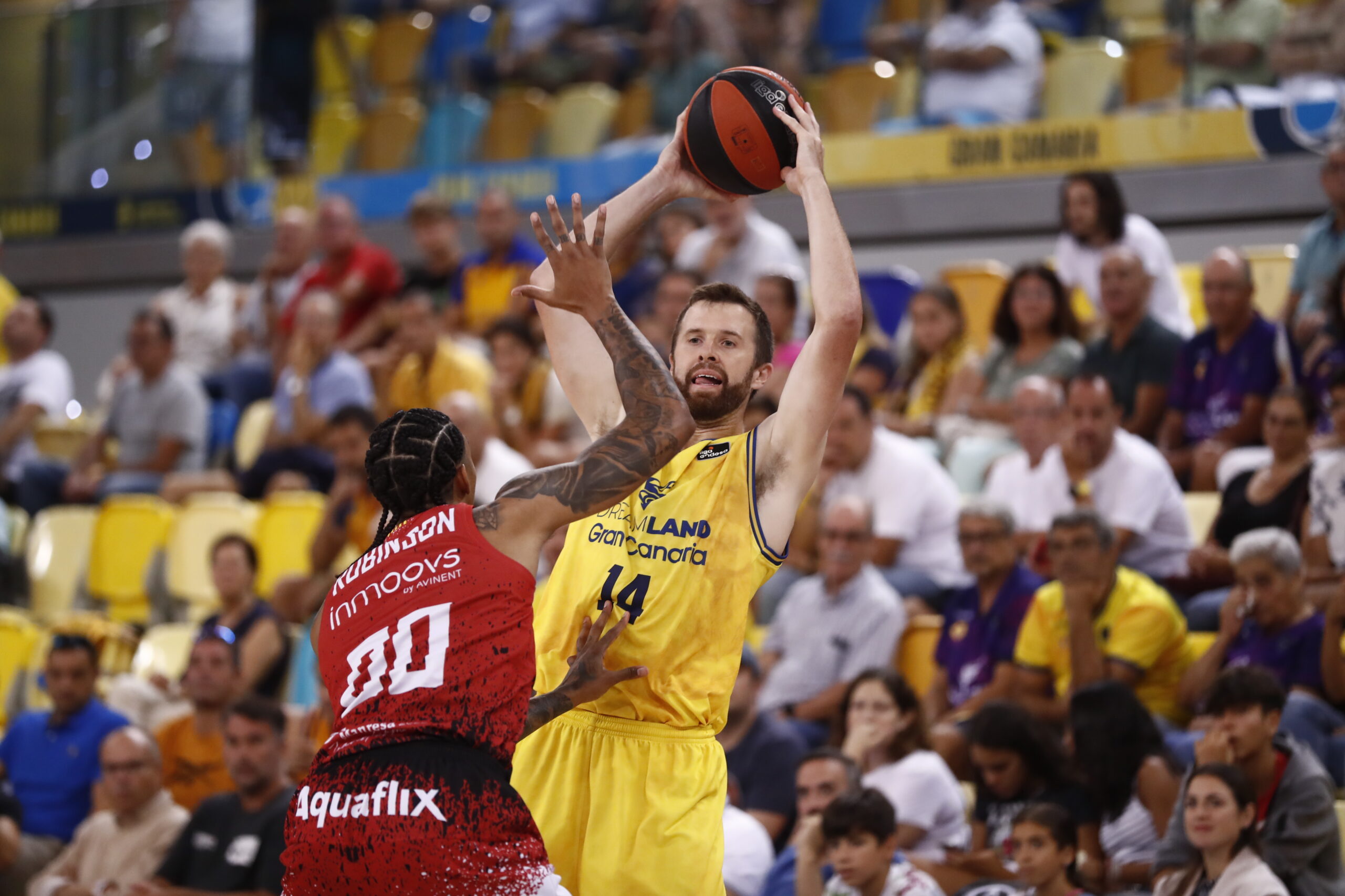 Jugador del Dreamland Gran Canaria lanza el balón mientras es defendido por un oponente.